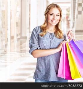 Happy customer with colourful paper bag in great mall, attractive girl enjoying shopping, buying gifts, spending money concept