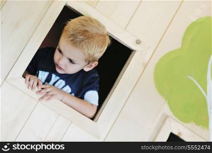 happy cute child in a wooden window at playground
