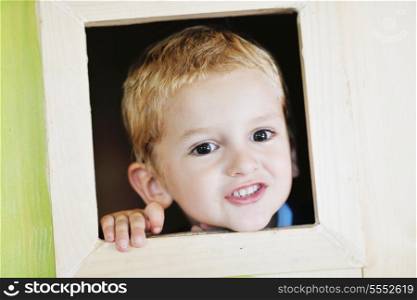 happy cute child in a wooden window at playground