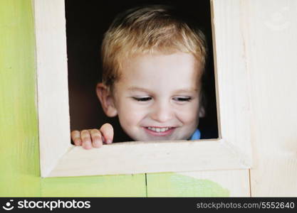 happy cute child in a wooden window at playground