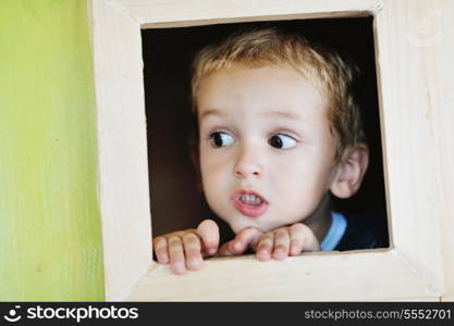 happy cute child in a wooden window at playground