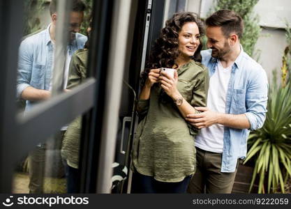 Happy cute couple in love embracing each other and drinking coffee at home by the window