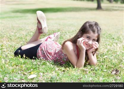 happy cute girl laying on a grass field and looking stright ,outdoor