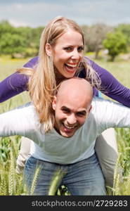 Happy cute woman being piggy backed by her boyfriend in outdoors