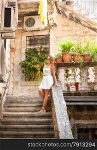 Happy cute woman standing on stone staircase at yard at sunny day