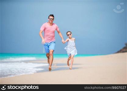 Happy dad and little baby at white sandy beach having fun. Family of father and sporty little girl having fun on the beach