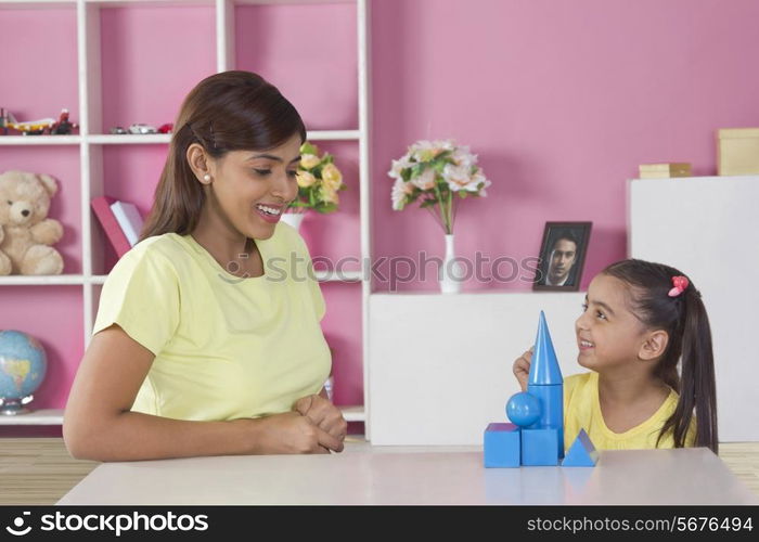 Happy daughter and mother playing with blocks at home