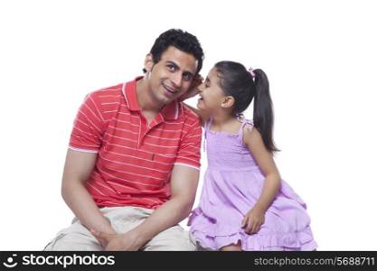 Happy daughter whispering in father&rsquo;s ear over white background