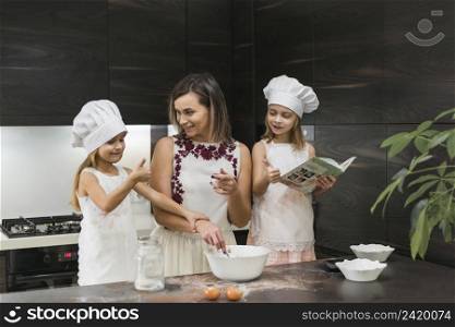 happy daughters wearing chef hat with mother preparing food kitchen