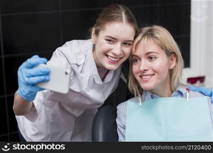 happy dentist taking selfie with patient