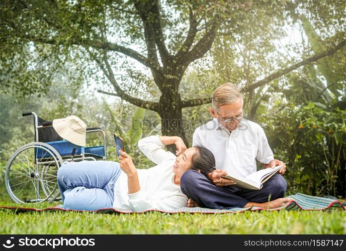 Happy disabled grandfather relaxing with granddaughter outdoor at the park. Family happy lifestyle.