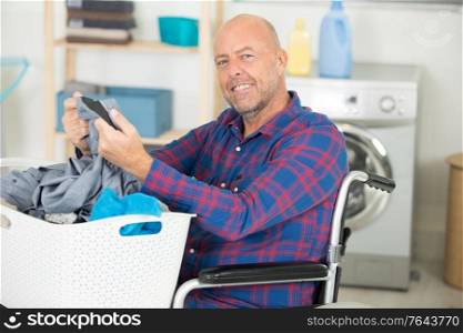 happy disabled man on wheelchair doing laundry