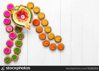 Happy Diwali - Clay Diya lamps lit during Dipavali, Hindu festival of lights celebration. Colorful traditional oil lamp diya on white wooden background