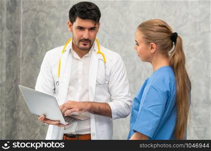 Happy doctor and nurse working with laptop computer in hospital office. Healthcare and medical concept.