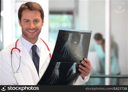 Happy doctor looking at x-ray image of hand