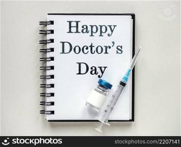 Happy Doctor&rsquo;s Day. Syringes, injection vials and a notepad lying on the table. Close-up, indoors, view from above. Day light, studio photo. Healthcare concept. Happy Doctor&rsquo;s Day. Syringes, injection vials and a notepad