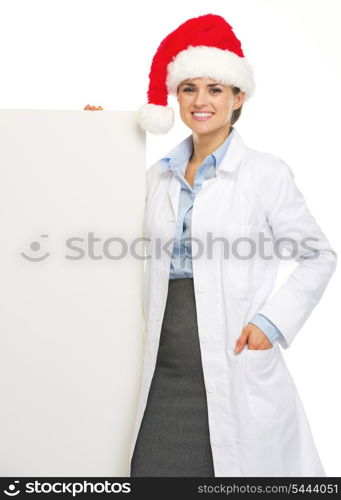 Happy doctor woman in santa hat showing blank billboard