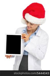 Happy doctor woman in santa hat showing tablet pc blank screen