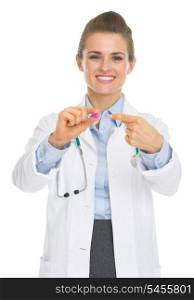 Happy doctor woman pointing on pill