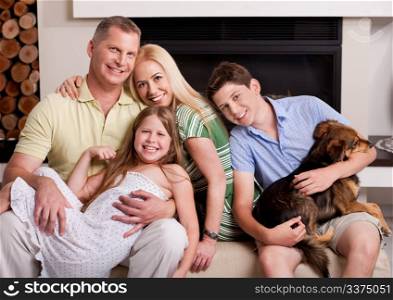 Happy domestic family sitting in living room with dog and looking at you
