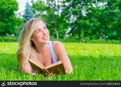 happy dreamy girl reading a book in the park