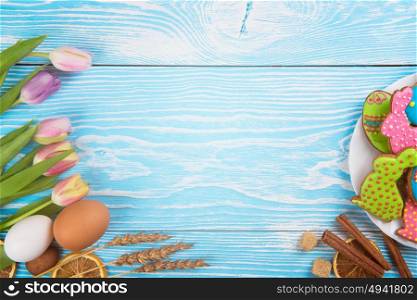 Happy easter coming. Composition of tulips and gingerbread cookies on white and blue wooden background for Happy Easter.