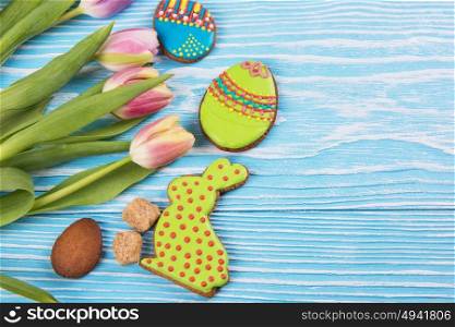 Happy easter coming. Composition of tulips and gingerbread cookies on white and blue wooden background for Happy Easter.