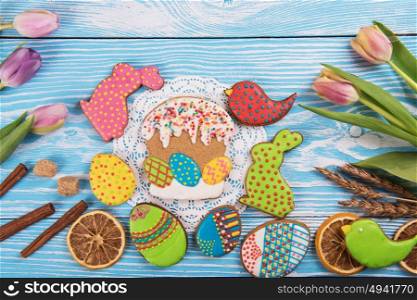 Happy Easter coming. Tulips and gingerbread cookies on white and blue wooden background for Easter.
