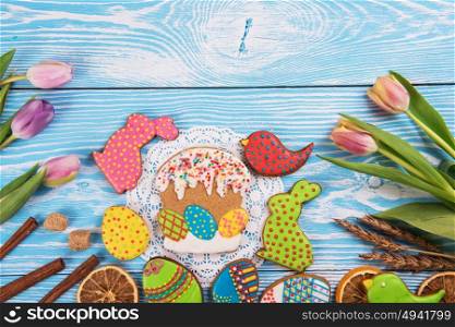 Happy Easter coming. Tulips and gingerbread cookies on white and blue wooden background for Easter.