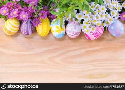 Happy Easter day colorful eggs and flowers on wooden floor with copy space.