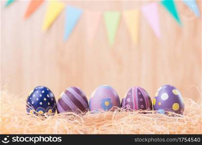 Happy Easter day colorful eggs on nest with blurred celebrate banner party flags with copy space.