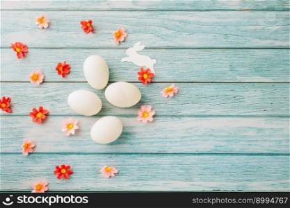 Happy Easter Day Concept. Top view of holiday banner background design white easter eggs and spring flowers on blue wooden background with empty copy space, celebration greeting card