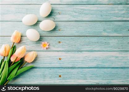 Happy Easter Day Concept. Top view of holiday banner background design white easter eggs and spring tulip flowers on blue wooden background with empty copy space, celebration greeting card