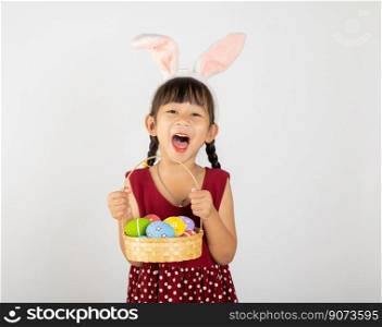 Happy Easter Day. Smile Asian little girl wearing easter bunny ears holding basket of full colorful eggs smiles broadly isolated on white background with copy space, Happy child in holiday