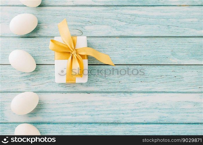 Happy Easter Day. Top view holiday banner background design with easter white eggs and gift box on blue wooden background with copy space