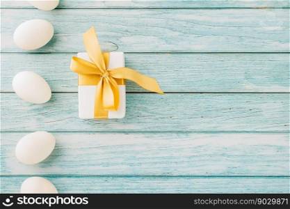 Happy Easter Day. Top view holiday banner background design with easter white eggs and gift box on blue wooden background with copy space
