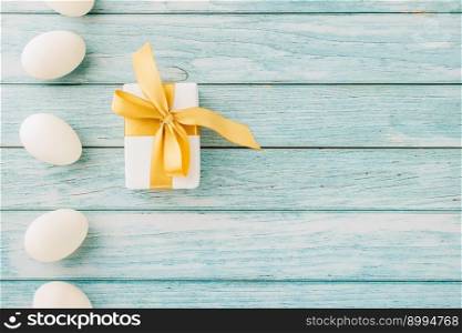 Happy Easter Day. Top view holiday banner background design with white easter eggs and gift box on blue wooden background with copy space, celebration greeting card