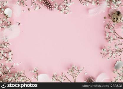 Happy Easter frame with flowers, feathers and egg shells on pink background, flat lay, copy space