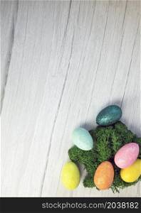 Happy Easter holliday concept, colorful easter eggs with green moss on white wooden background texture top view, copy space, bright colors space for text. Happy Easter holliday concept, colorful easter eggs with green moss on white wooden background texture top view, copy space, bright colors