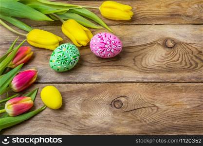 Happy Easter rustic greeting card with pink and green floral decorated painted eggs and tulips, copy space.