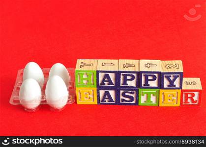 Happy easter spelled with colorful alphabet blocks with white easter eggs isolated on a red background