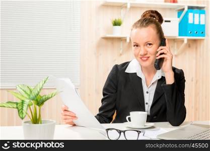 Happy economist with documents and phone in office