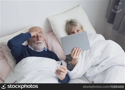 happy elderly couple caucasian senior man conferrencing with family by using on tablet in white blanket in bedroom, retirement love family lifestyle concept