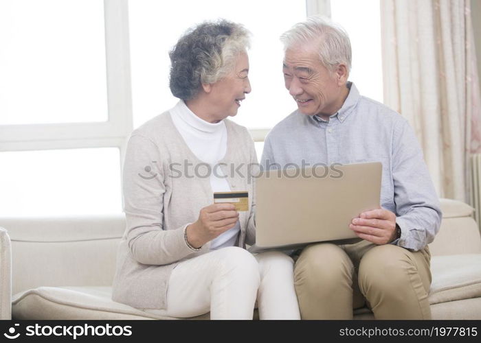 Happy elderly couple shopping online on a laptop