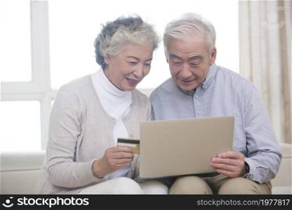 Happy elderly couple shopping online on a laptop