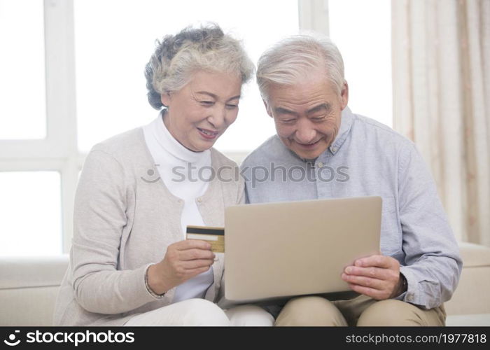 Happy elderly couple shopping online on a laptop