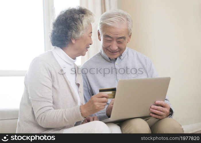 Happy elderly couple shopping online on a laptop