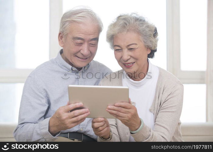 Happy elderly couples using a tablet computer