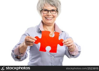 Happy elderly woman holding a puzzle piece, isolated on white background