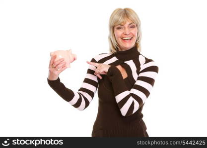 Happy elderly woman pointing on piggy bank